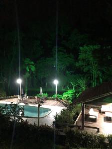 a night view of a swimming pool with lights at Sítio Bagatelle com cachoeira e piscina! in Angra dos Reis