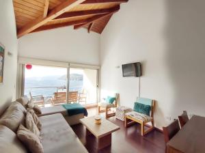 ein Wohnzimmer mit einem Sofa, Stühlen und einem TV in der Unterkunft Quinta Luna NH in San Carlos de Bariloche