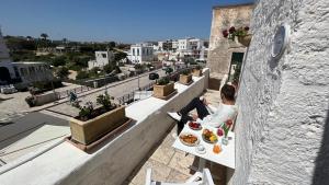 un uomo seduto a un tavolo su un balcone con cibo di Antico Mondo Rooms & Suites a Polignano a Mare