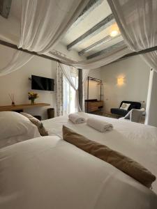 una camera con 2 letti bianchi e un soggiorno di Antico Mondo Rooms & Suites a Polignano a Mare