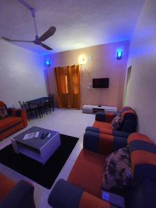a living room with couches and a table and a tv at Appartement Meuble AU GOLF Bamako in Bamako
