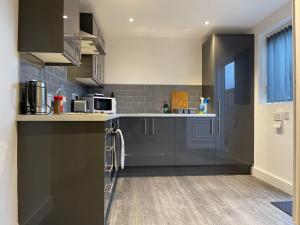 a kitchen with black cabinets and a counter top at Modern Serviced Apartment - Near City Centre in Doncaster