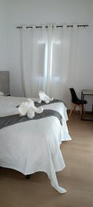 a bedroom with a bed with white sheets and a window at Pensión Mar in Portomarin