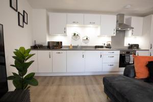 a kitchen with white cabinets and a couch in a room at The Courtyard- Free evening parking in Southampton