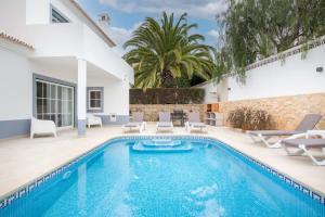 uma piscina com cadeiras e uma villa em Villa Estrella - Praia da Luz na Praia da Luz