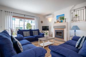 uma sala de estar com sofás azuis e uma lareira em Villa Estrella - Praia da Luz na Praia da Luz