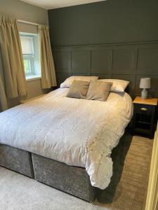 a bedroom with a large bed with white sheets at Emelia Cottage Ingleton in Ingleton