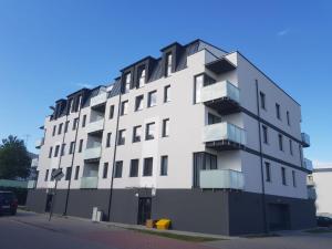 a white building with balconies on a street at Apartamant Oaza II in Koszalin