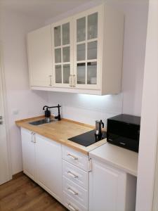 a kitchen with white cabinets and a sink and a microwave at Kapitány apartman in Siófok