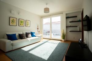 a living room with a white couch and a large window at Downtown PDL in Ponta Delgada +7 photos