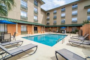 une piscine dans un hôtel avec des chaises longues et un hôtel dans l'établissement Holiday Inn Express Hotel & Suites Bluffton at Hilton Head Area, an IHG Hotel, à Bluffton