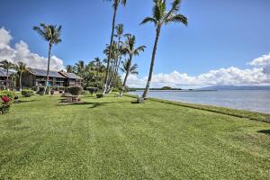 une pelouse avec des palmiers, une maison et l'eau dans l'établissement Molokai Island Loft Lanai, Pool and Walk to Beach!, à Kaunakakai