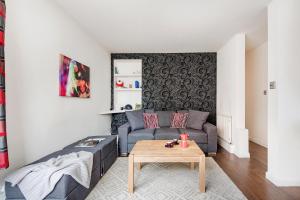 uma sala de estar com um sofá e uma mesa em Bright and stylish apartment in trendy Islington by UnderTheDoormat em Londres