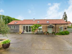 a brick house with a driveway in front of it at Brook Cottage in Stearsby