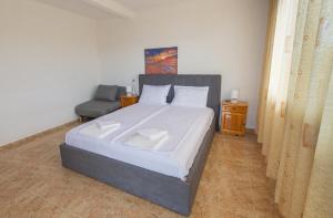 a bedroom with a large bed and a chair at Vila Rosen in Lozenets
