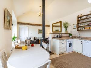 a kitchen and living room with a white table in a room at Brook Cottage in Stearsby