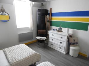 a bedroom with a dresser and a striped wall at les volets bleus in Saint-Guénolé