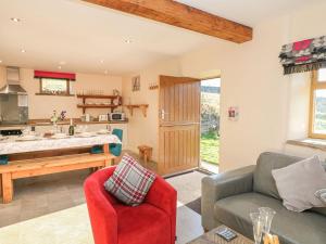 a living room with a couch and a kitchen at Columbine Barn in Bradwell