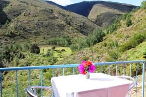 una mesa con un jarrón de flores en el balcón en Suites Arcoiris, en Villa de Leyva