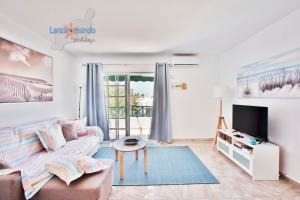 Una sala de estar con un sofá y un televisor. en Vivienda Vacacional El Tucan, en Tías