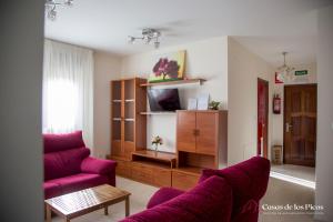 uma sala de estar com duas cadeiras roxas e uma televisão em Chalet vacacional Tina Menor - Casas de los Picos em Pesués