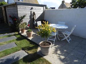 a patio with a table and chairs and plants at les volets bleus in Saint-Guénolé