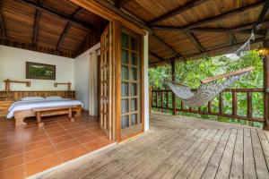 a bedroom with a hammock on a deck at Rancho Margot Sustainable & Self Sufficient Eco Lodge in El Castillo de La Fortuna