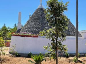 a building with a steep roof with a tree in front at Trulli Ulivi in Putignano