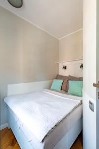a bedroom with a large white bed with green pillows at Apartament Kowalska Starówka in Elblag