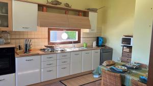 kuchnia z białymi szafkami, zlewem i stołem w obiekcie Villa Dolce Havana con piscina w mieście Sperlonga