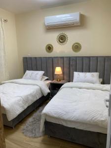 a bedroom with two beds and a air conditioner on the wall at Yas Hotel Apartments in Al Ain