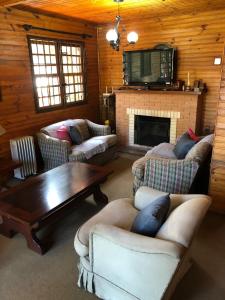 a living room with couches a table and a fireplace at Chalé Sonho da Vovó a 5 minutinhos do Centrinho de Capivari in Campos do Jordão