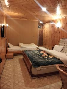 a bedroom with two beds in a room with wooden walls at Swiss Wood Cottages Naran in Nārān