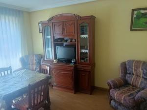 ein Wohnzimmer mit einem TV und einem hölzernen Entertainment-Center in der Unterkunft Apartamento Jardin del Sueve in Colunga