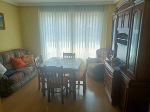 uma sala de estar com uma mesa, um sofá e uma televisão em Apartamento Jardin del Sueve em Colunga