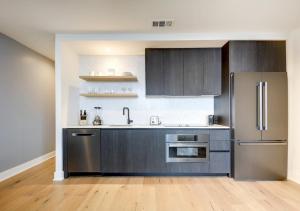 a kitchen with gray cabinets and a stainless steel refrigerator at Brand New - Spacious Luxury Condo, Steps from Lake & Rainey for 4 in Austin