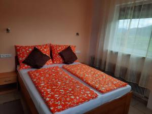 un letto con lenzuola arancioni e cuscini con finestra di Pension Horvath a Sankt Kanzian
