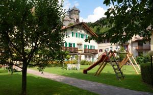 un parque infantil frente a una casa con tobogán en Parkhotel Post, en Chiusa