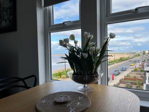 a vase of flowers on a table in front of a window at Seafront Luxury Apartment in Cleethorpes