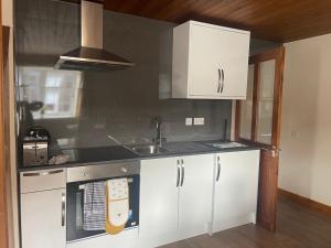 a kitchen with white cabinets and a sink at Fairladies Barn Guest House in St Bees