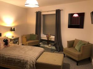 a bedroom with a bed and two chairs and a window at Ten Streets Apartment in Liverpool