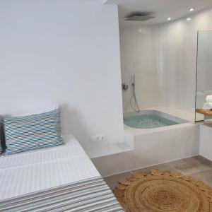 un bagno bianco con vasca, un letto e un tappeto di Drimoni Boutique a Ios Chora