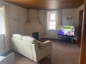 uma sala de estar com um sofá branco e uma televisão de ecrã plano em Fairladies Barn Guest House em St Bees