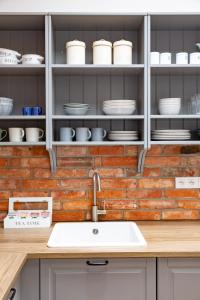 uma cozinha com um lavatório e uma parede de tijolos em Apartament Wigilijna Premium Starówka em Elblag