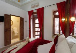 a bedroom with a bed with red curtains and a mirror at Riad Morocco Sky in Marrakesh