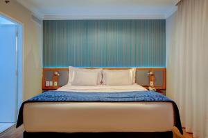 a bedroom with a large bed with a blue wall at Quality Suítes Oscar Freire in Sao Paulo