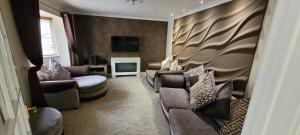 a living room with two couches and a television at Tides Reach - 3 Bedroom Holiday Home - Llanreath in Pembrokeshire