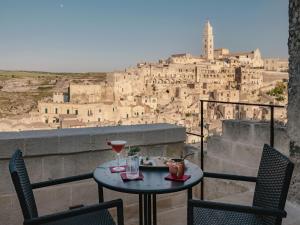 een tafel met een drankje en 2 stoelen op een balkon bij Palazzo Degli Abati in Matera