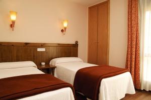 a hotel room with two beds and a window at Hotel Pirineos in Castejón de Sos