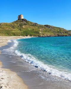 a beach with a lighthouse on top of a hill at WEST SARDINIA APARTMENT 3 in Càbras